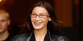 Bella Hadid oozes off duty chic in a plunging bodysuit and leather jacket as she waves to fans while departing her hotel in Paris during fashion week