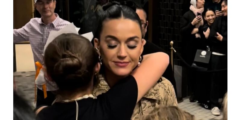 Katy Perry sweetly hugs a young fan as she signs autographs outside her Melbourne hotel after her AFL Grand Final headlining gig