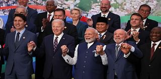 Biden finally makes it to his G20 group photo with a little jog... after emerging behind a palm tree to miss the last